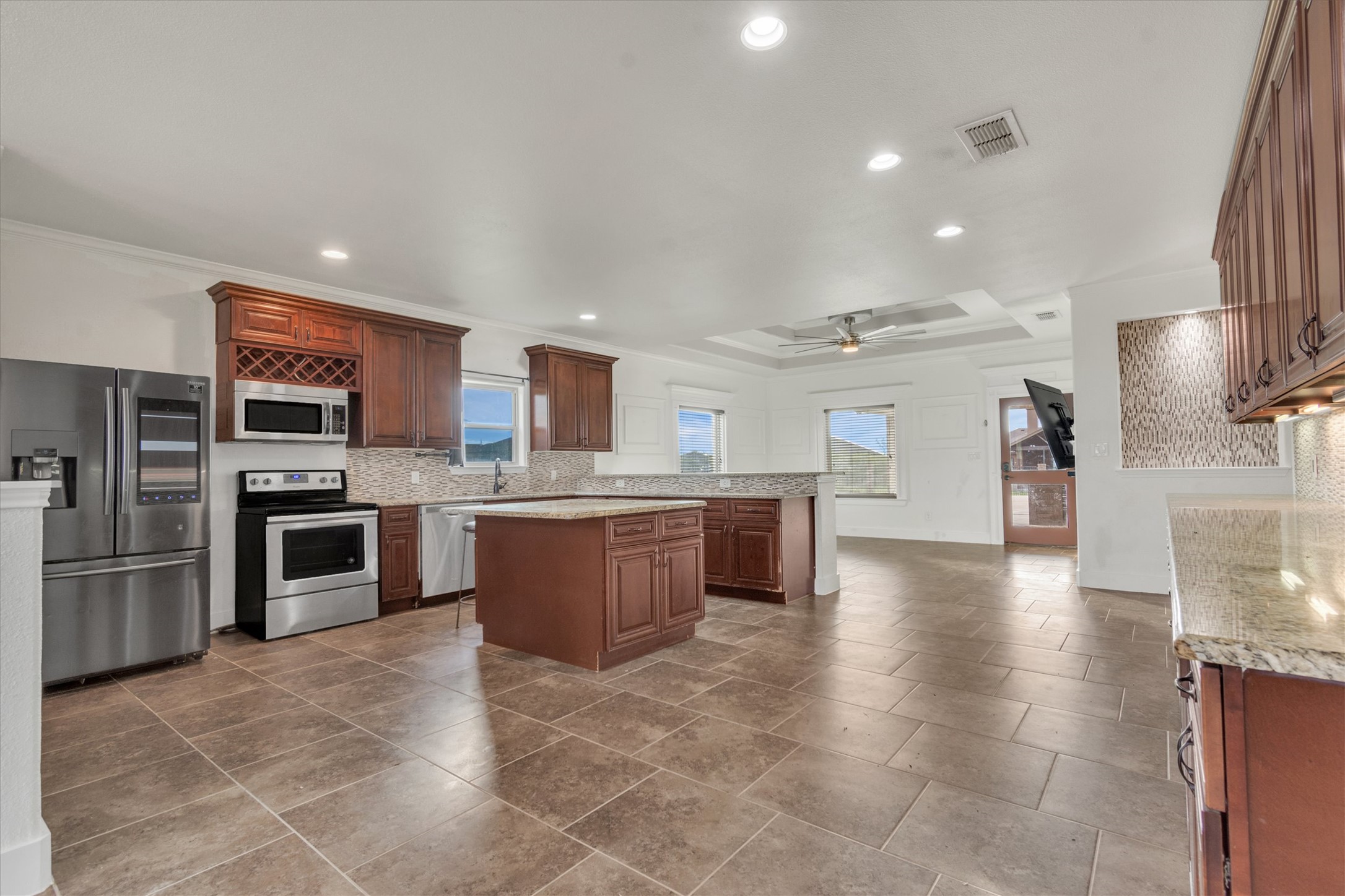 164 Peck Street Kyle, TX 78640 - Photo 5 of 19 Kitchen featuring stainless steel appliances, a kitchen island, ceiling fan, backsplash, and a raised ceiling