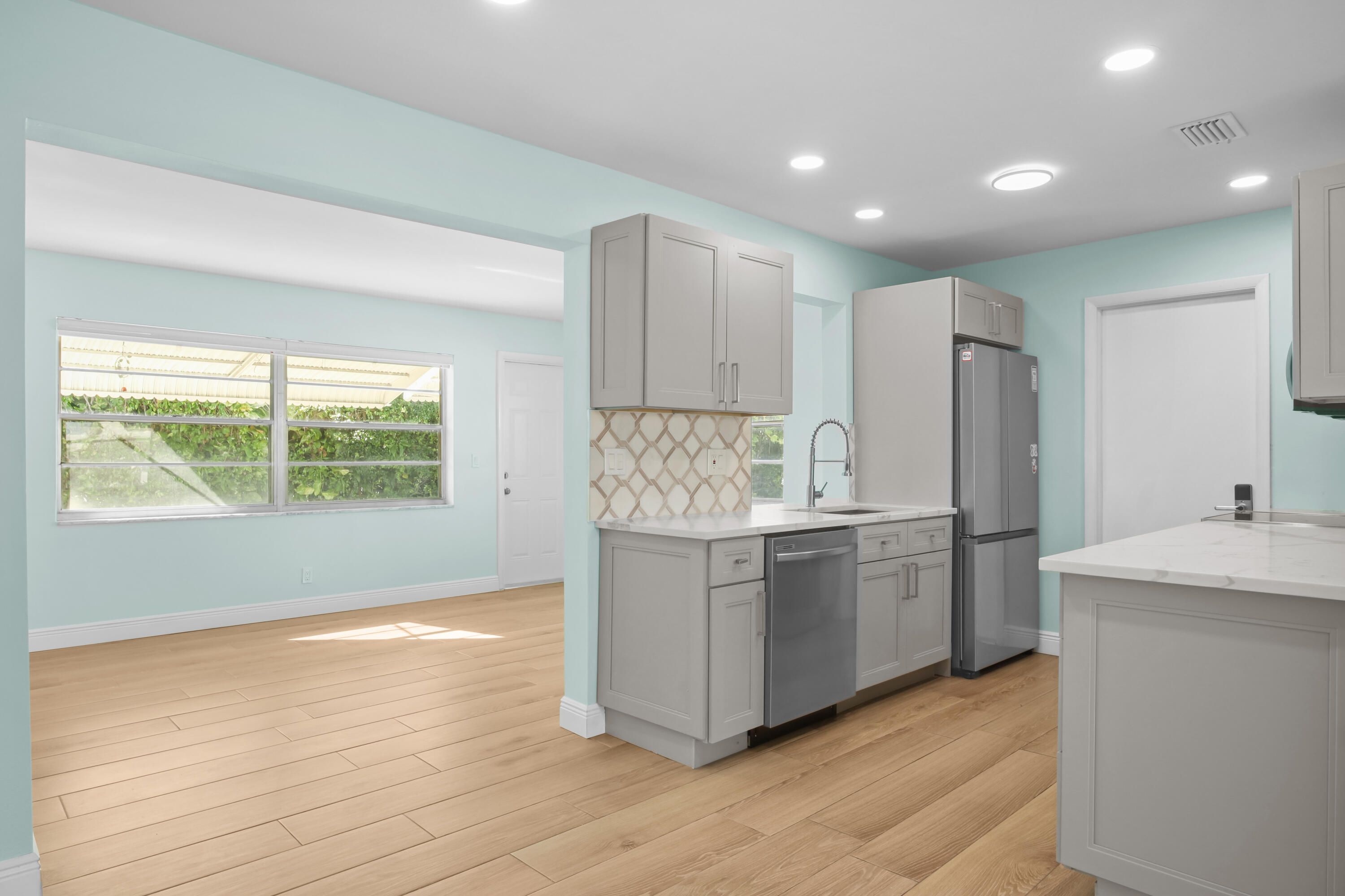 1308 Southwest 24th Street Boynton Beach, FL 33426 - Photo 6 of 19 a kitchen with kitchen island granite countertop a stove a sink a refrigerator and white cabinets with wooden floor