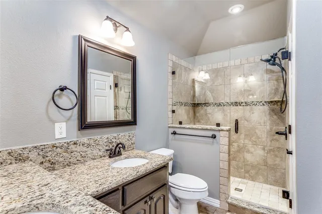 a bathroom with a granite countertop sink toilet a mirror and shower