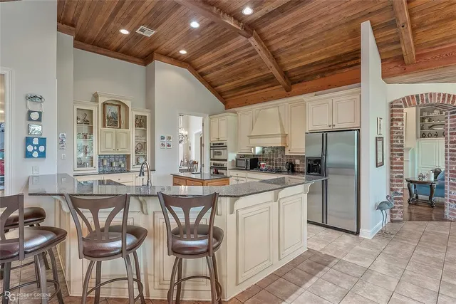 a kitchen with stainless steel appliances kitchen island granite countertop a table chairs and a refrigerator