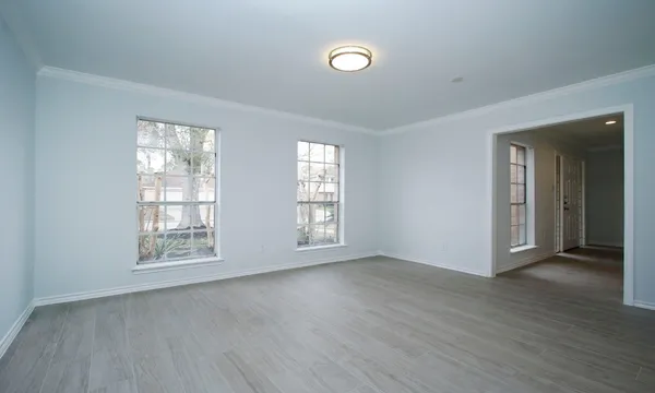 an empty room with wooden floor and windows