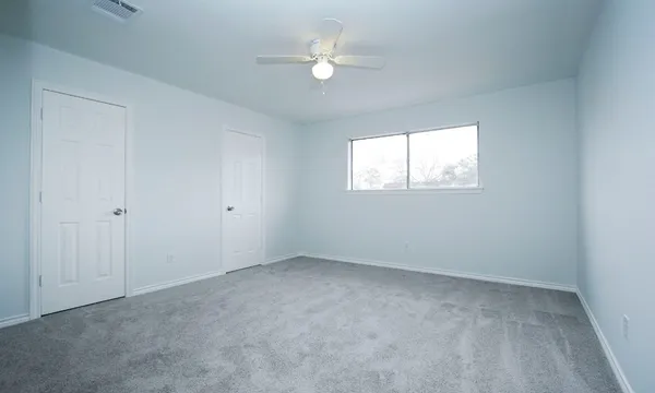 an empty room with a window and a fan