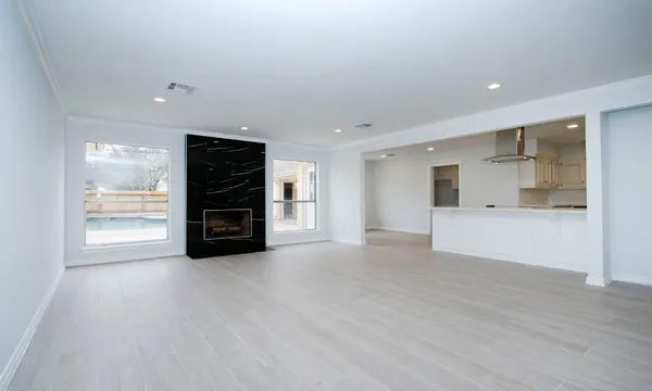 a view of an empty room with a kitchen and window