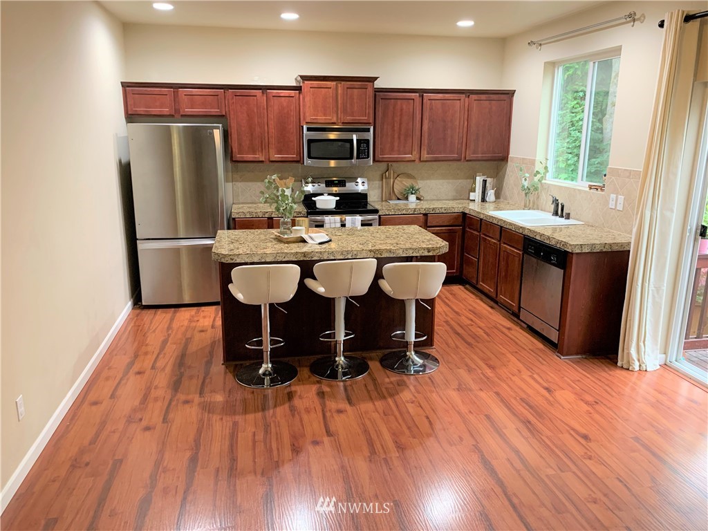273 Graham Avenue Northeast Renton, WA 98059 - Photo 9 of 23 a kitchen with stainless steel appliances a refrigerator a sink a stove a microwave and wooden floor
