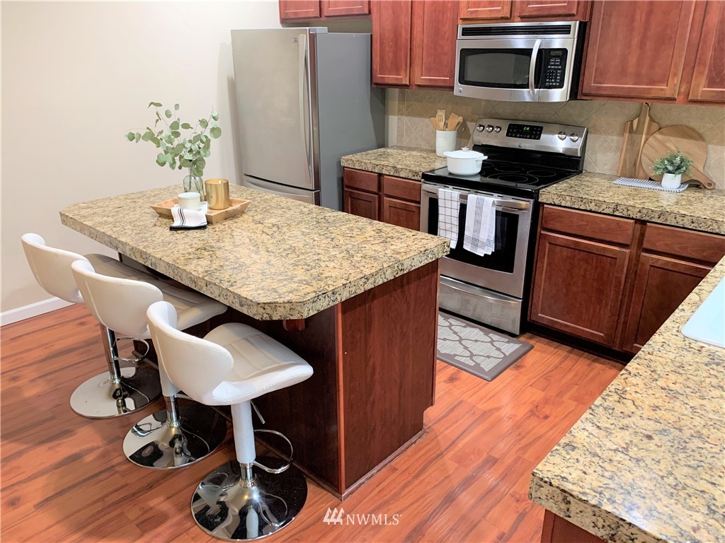 273 Graham Avenue Northeast Renton, WA 98059 - Photo 10 of 23 a kitchen with granite countertop a table chairs stove and cabinets