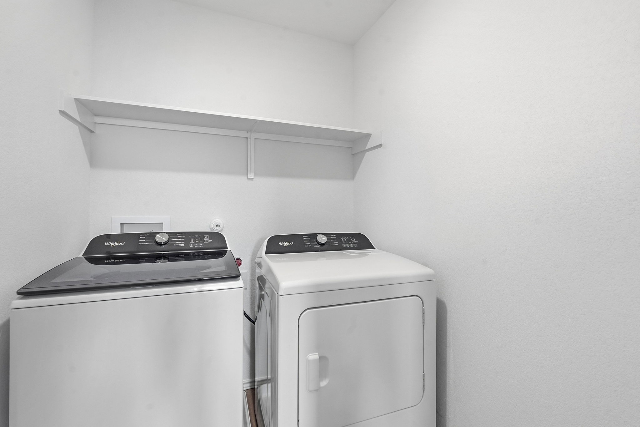 164 Cinnabar Lane, Unit 5 Kyle, TX 78640 - Photo 18 of 21 Dedicated laundry area featuring a top-load washing machine, front-load dryer, and an overhead storage shelf