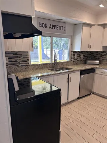 a kitchen with stainless steel appliances granite countertop a stove a sink and a microwave