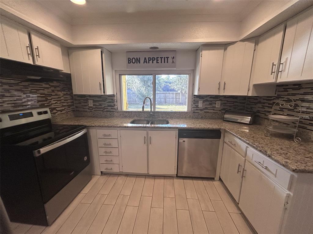 1495 Bishop Road Spring Hill, FL 34608 - Photo 24 of 34 a kitchen with stainless steel appliances granite countertop a stove a sink and a microwave