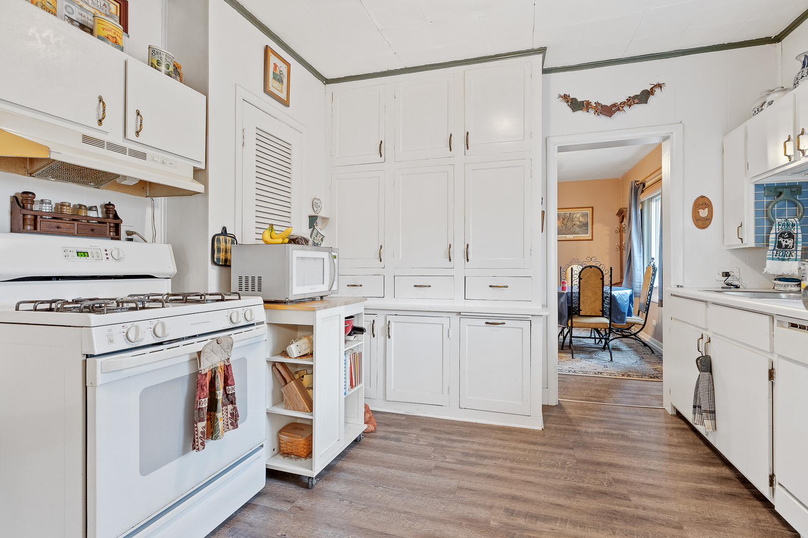 5714 East 3500S Road St. Anne, IL 60964 - Photo 11 of 35 a kitchen with white cabinets and white appliances