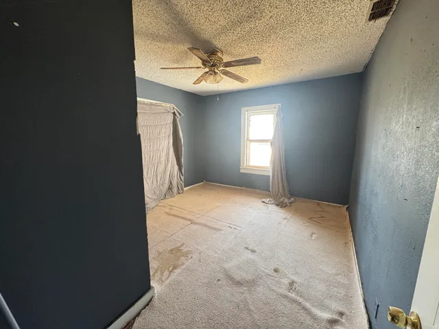 an empty room with a ceiling fan and window