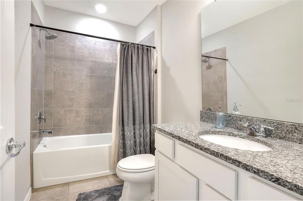 1623 Aspen Avenue Davenport, FL 33837 - Photo 26 of 43 a bathroom with a granite countertop sink toilet mirror and bathtub