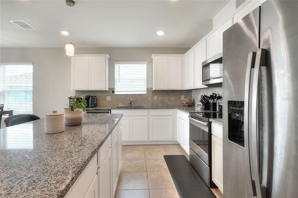 1623 Aspen Avenue Davenport, FL 33837 - Photo 5 of 43 a kitchen with stainless steel appliances granite countertop a refrigerator sink and stove