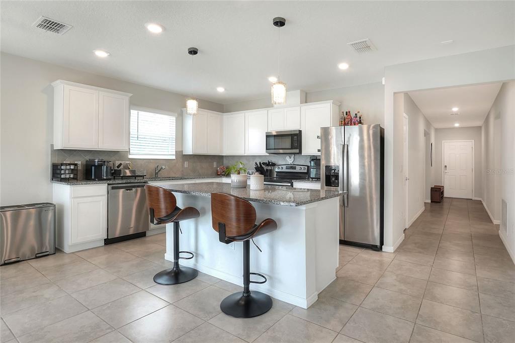 1623 Aspen Avenue Davenport, FL 33837 - Photo 9 of 43 a kitchen with kitchen island granite countertop a stove a sink a refrigerator and cabinets