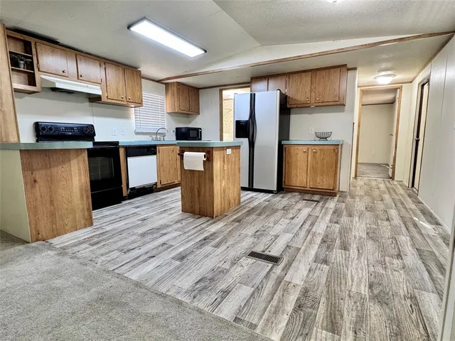 a kitchen with stainless steel appliances kitchen island granite countertop a refrigerator and a sink