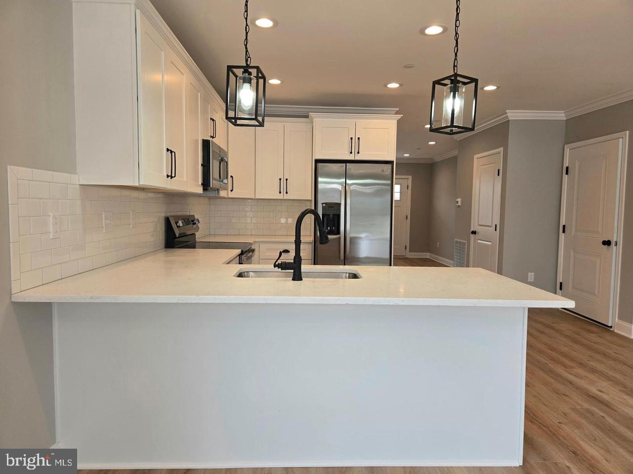8478 Garden Road Pasadena, MD 21122 - Photo 4 of 14 a kitchen with kitchen island stainless steel appliances a sink cabinets and wooden floor