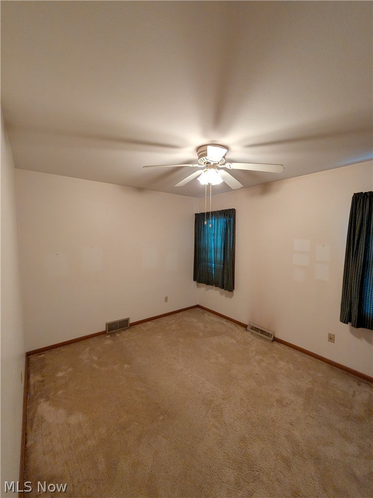1161 Gulf Road Elyria, OH 44035 - Photo 24 of 34 Carpeted room featuring a ceiling fan with integrated lighting, two windows with vertical blinds, and baseboard trim