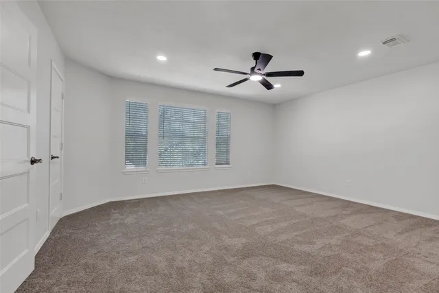 an empty room with ceiling fan and windows