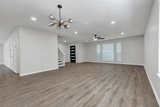 a view of an empty room with wooden floor windows and a chandelier