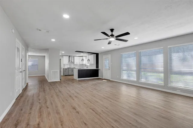 a view of empty room with wooden floor and fan