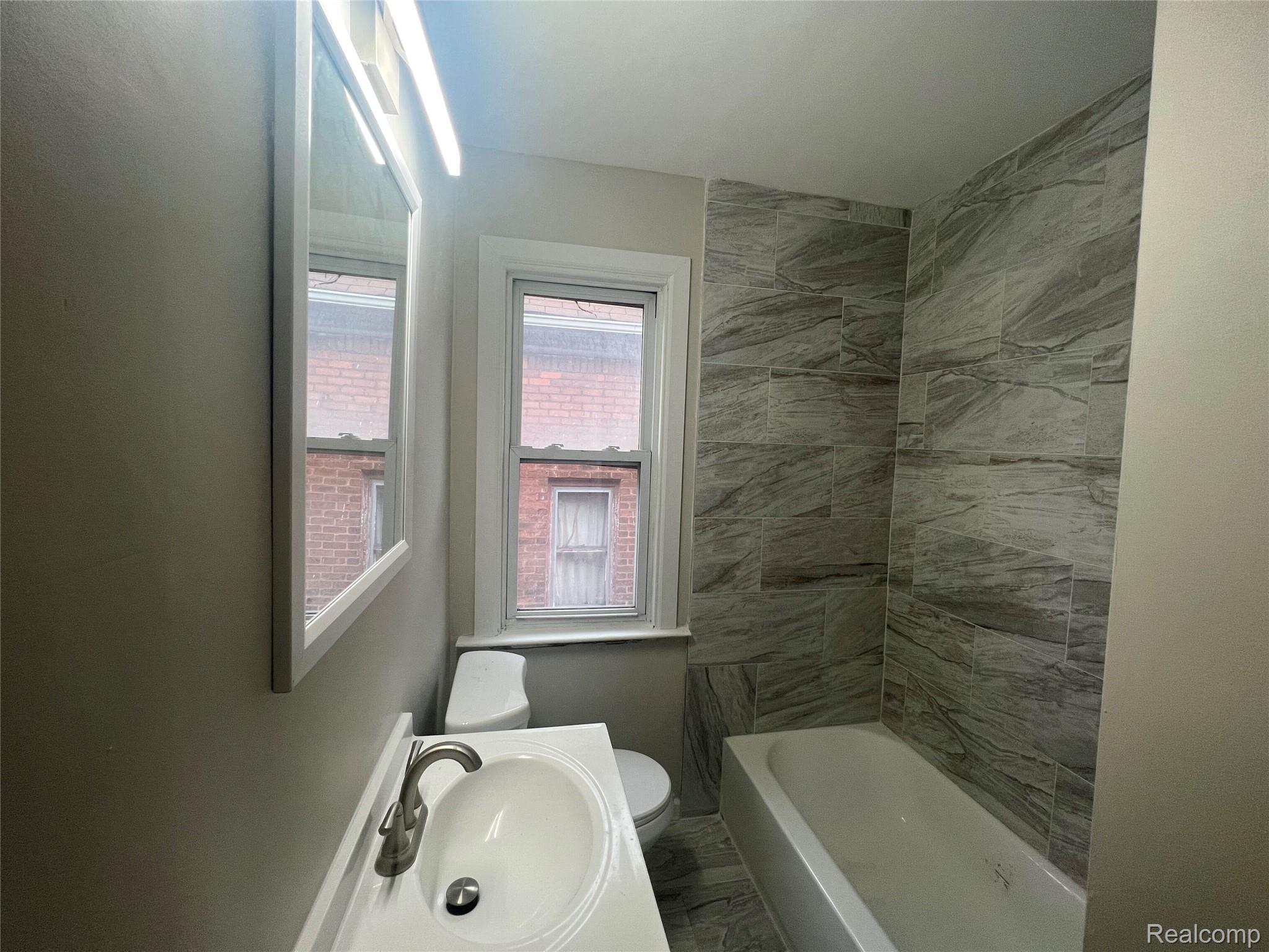 3020 Clements Street Detroit, MI 48238 - Photo 6 of 11 Bathroom featuring a single window, vanity with an integrated sink, brushed nickel faucet, and a tiled shower-over-tub