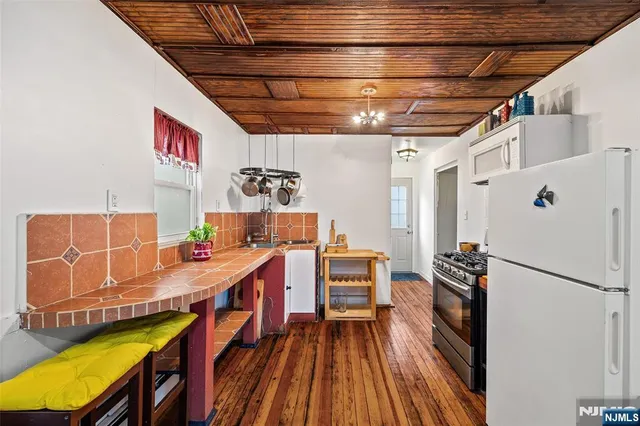 a utility room with stainless steel appliances wooden floor a stove and a refrigerator