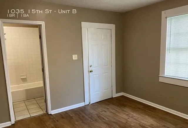 an empty room with wooden floor cabinet and windows