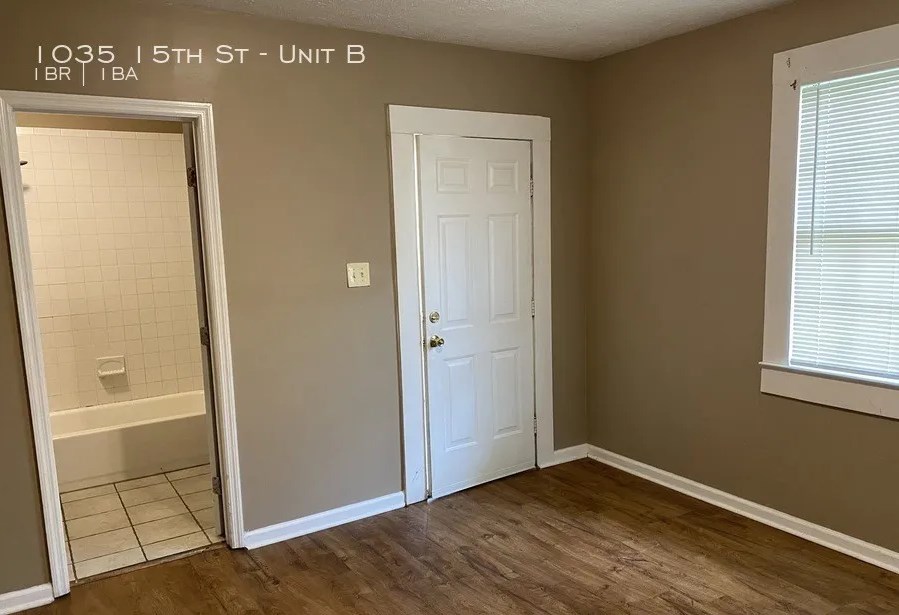 1035 15th Street, Unit B Columbus, GA 31901 - Photo 2 of 8 an empty room with wooden floor cabinet and windows