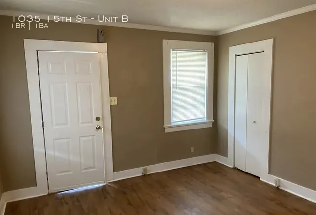 an empty room with wooden floor closet and windows