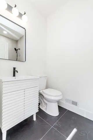 a bathroom with a white toilet sink and mirror