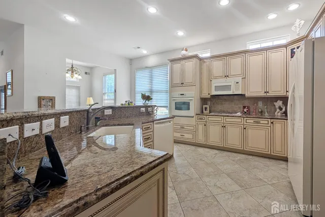 a kitchen with kitchen island granite countertop a sink counter top space appliances and cabinets
