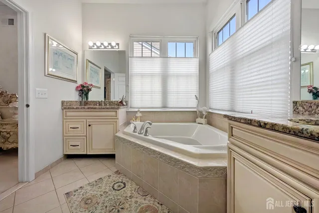 a spacious bathroom with a tub sink and mirror