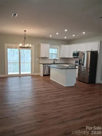 a kitchen with granite countertop a refrigerator and a stove top oven