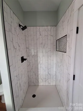 a view of a hallway with wooden floor and a bathroom