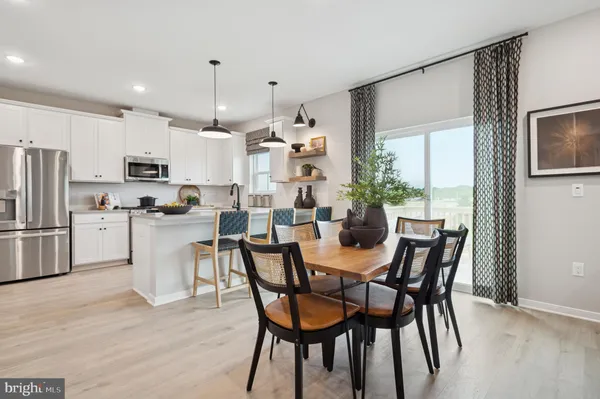 a kitchen with kitchen island a dining table chairs stainless steel appliances and cabinets