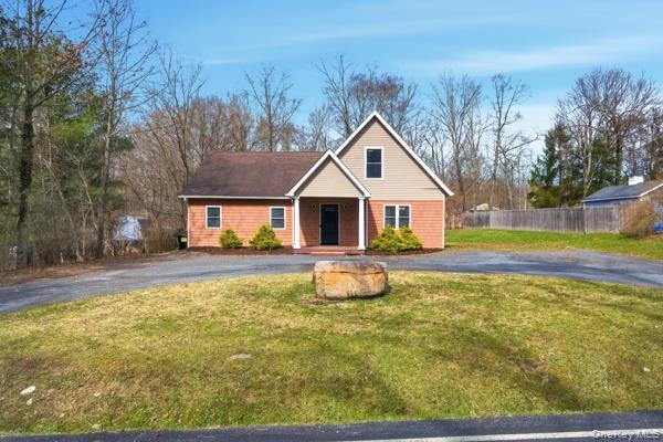 contemporary home with covered porch, u-shaped driveway, and a front yard