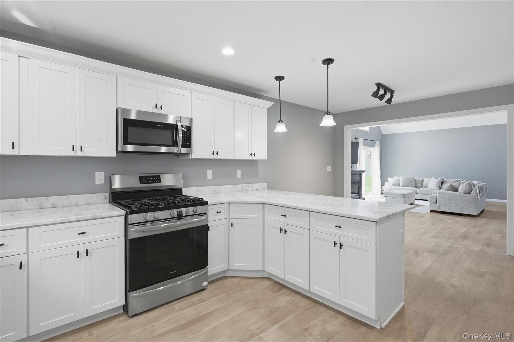 1227 Burlingham Road Pine Bush, NY 12566 - Photo 17 of 39 Kitchen with stainless steel appliances, white cabinets, light wood-style floors, hanging light fixtures, and peninsula