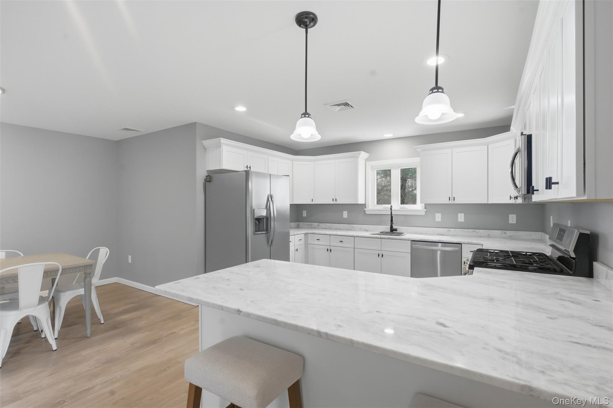 1227 Burlingham Road Pine Bush, NY 12566 - Photo 18 of 39 Kitchen featuring a breakfast bar area, white cabinets, stainless steel appliances, light granite countertops, and an island