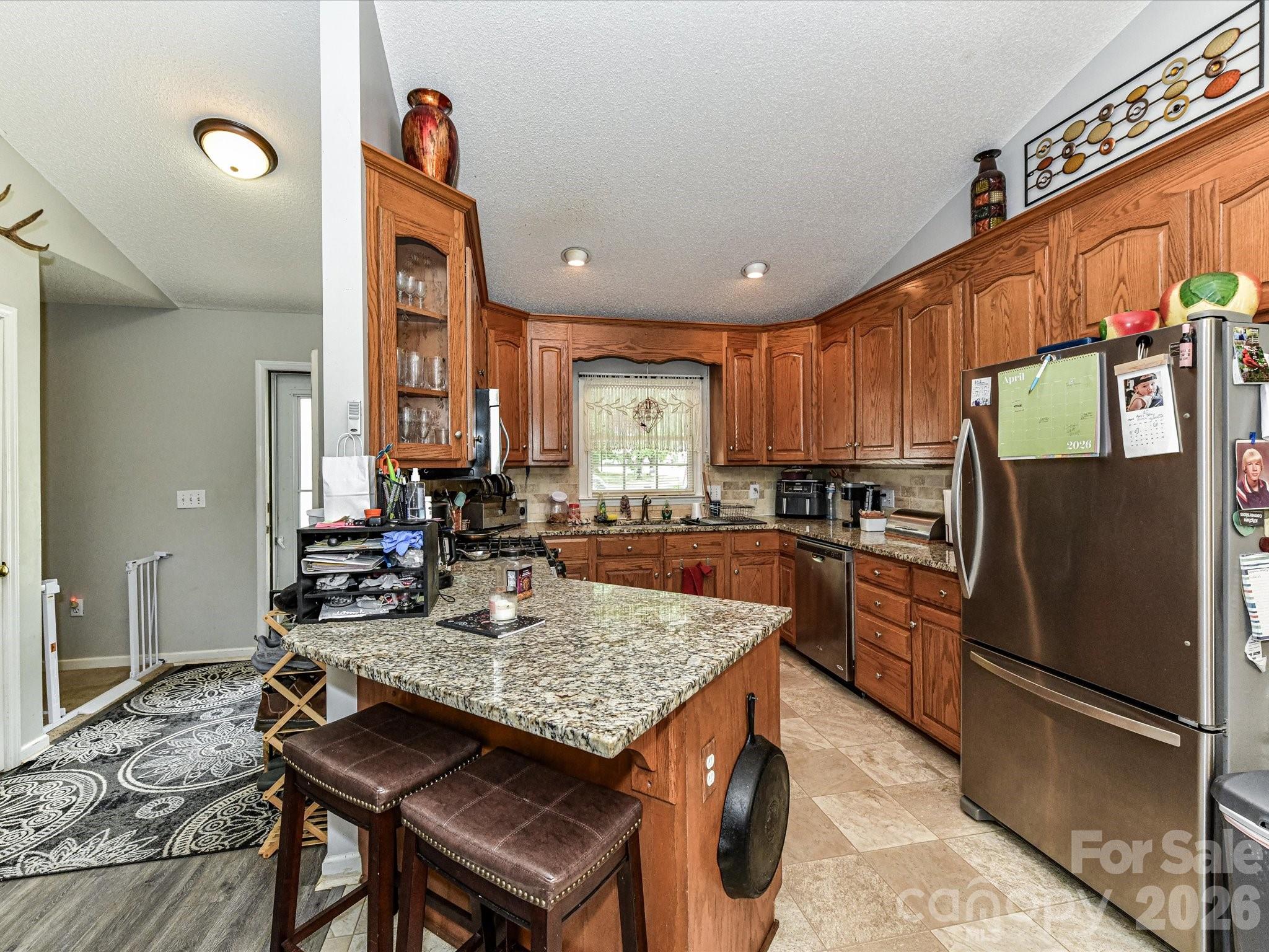 1472 Ridgewood Drive Concord, NC 28027 - Photo 11 of 30 a kitchen with a refrigerator a stove a sink and a dining table with wooden floor