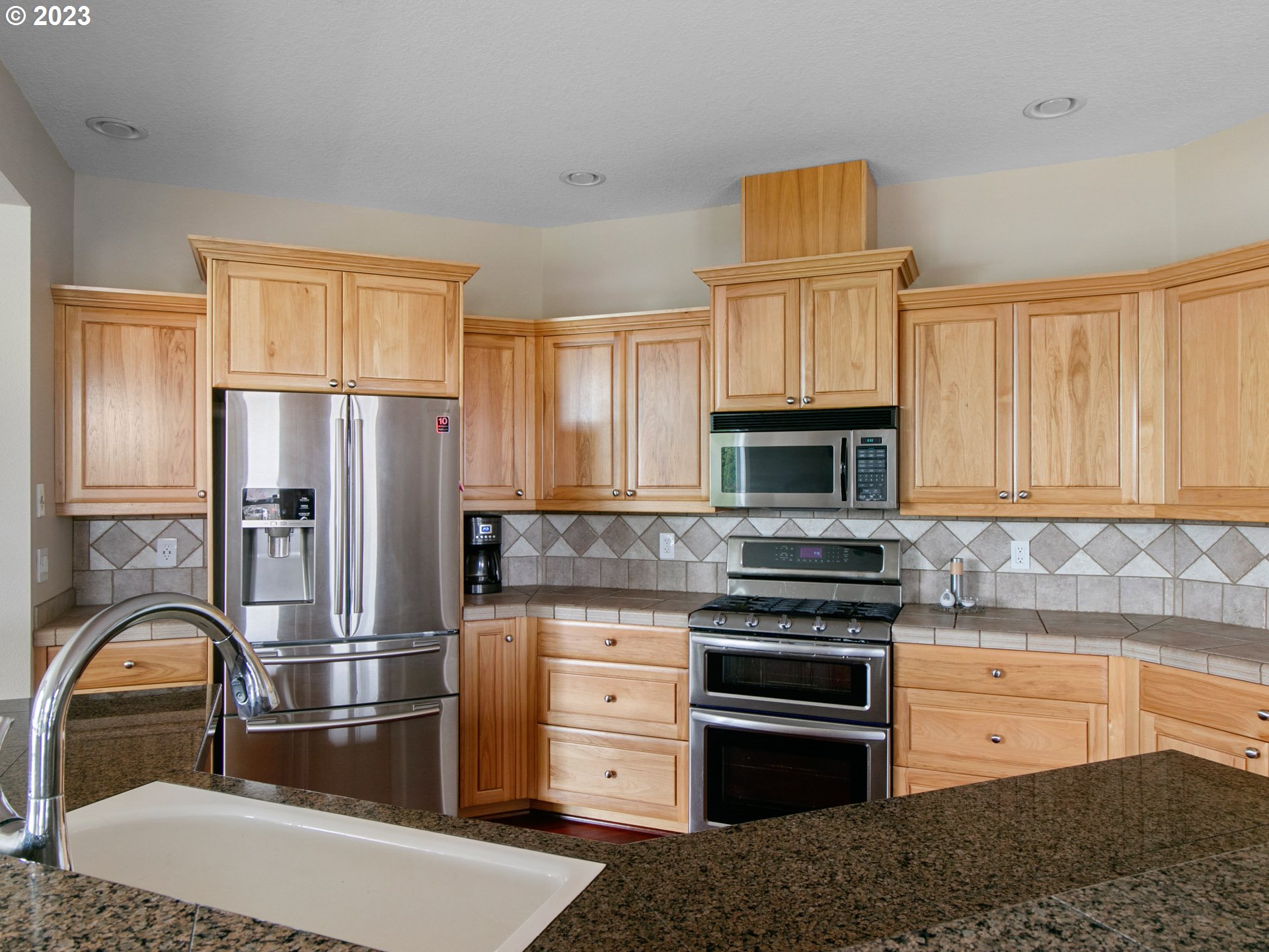 1156 Southeast Polk Street Camas, WA 98607 - Photo 14 of 34 a kitchen with granite countertop a refrigerator stove and wooden cabinets