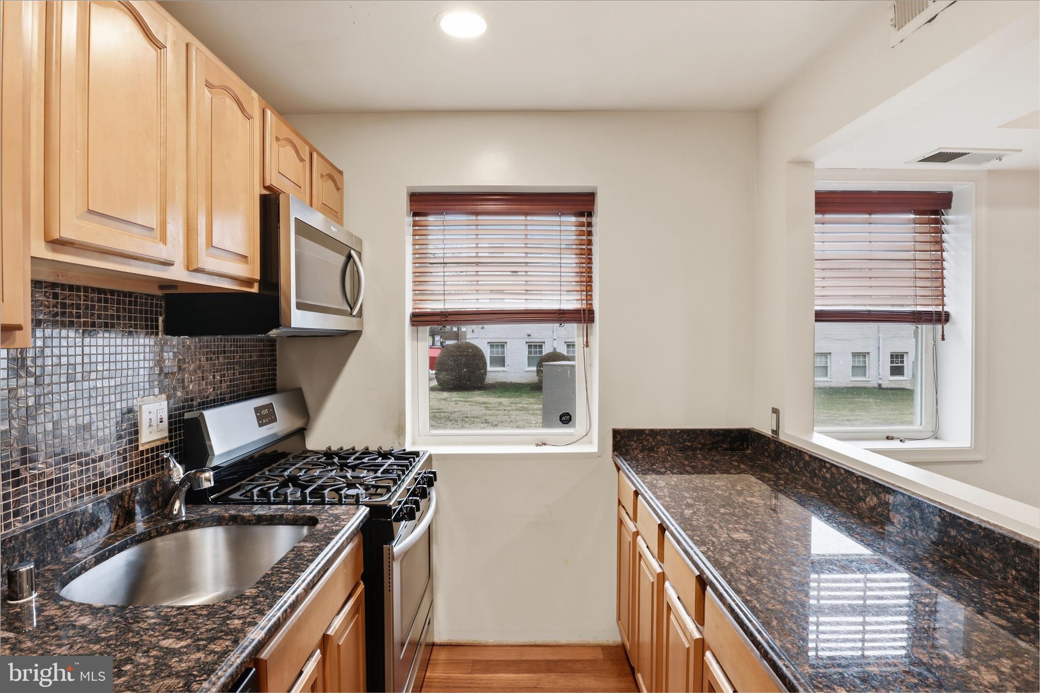 3866 9th Street Southeast, Unit 102 Washington, DC 20032 - Photo 6 of 21 a kitchen with granite countertop a sink stove and cabinets