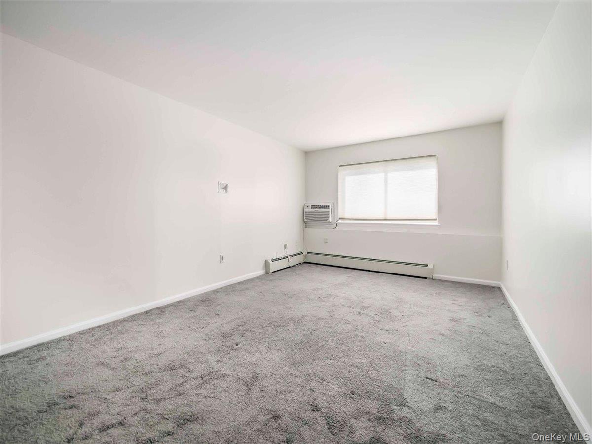 27 Tanager Road, Unit 2702 Monroe, NY 10950 - Photo 22 of 35 Neutral wall paint, gray carpeting, a window with horizontal blinds, and a wall-mounted air conditioning unit