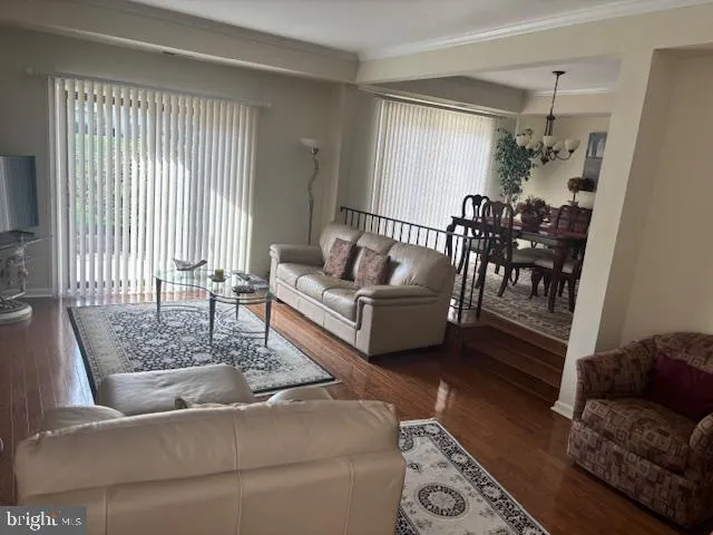 a living room with furniture kitchen view and a chandelier