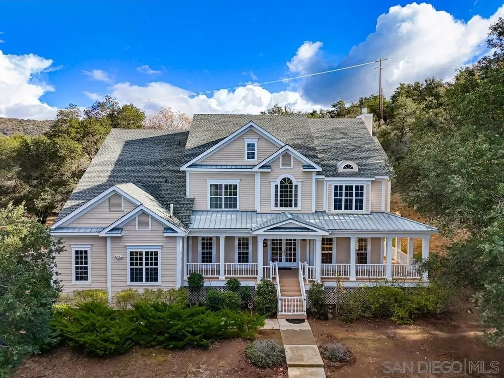 a view of a white house next to a yard with large trees