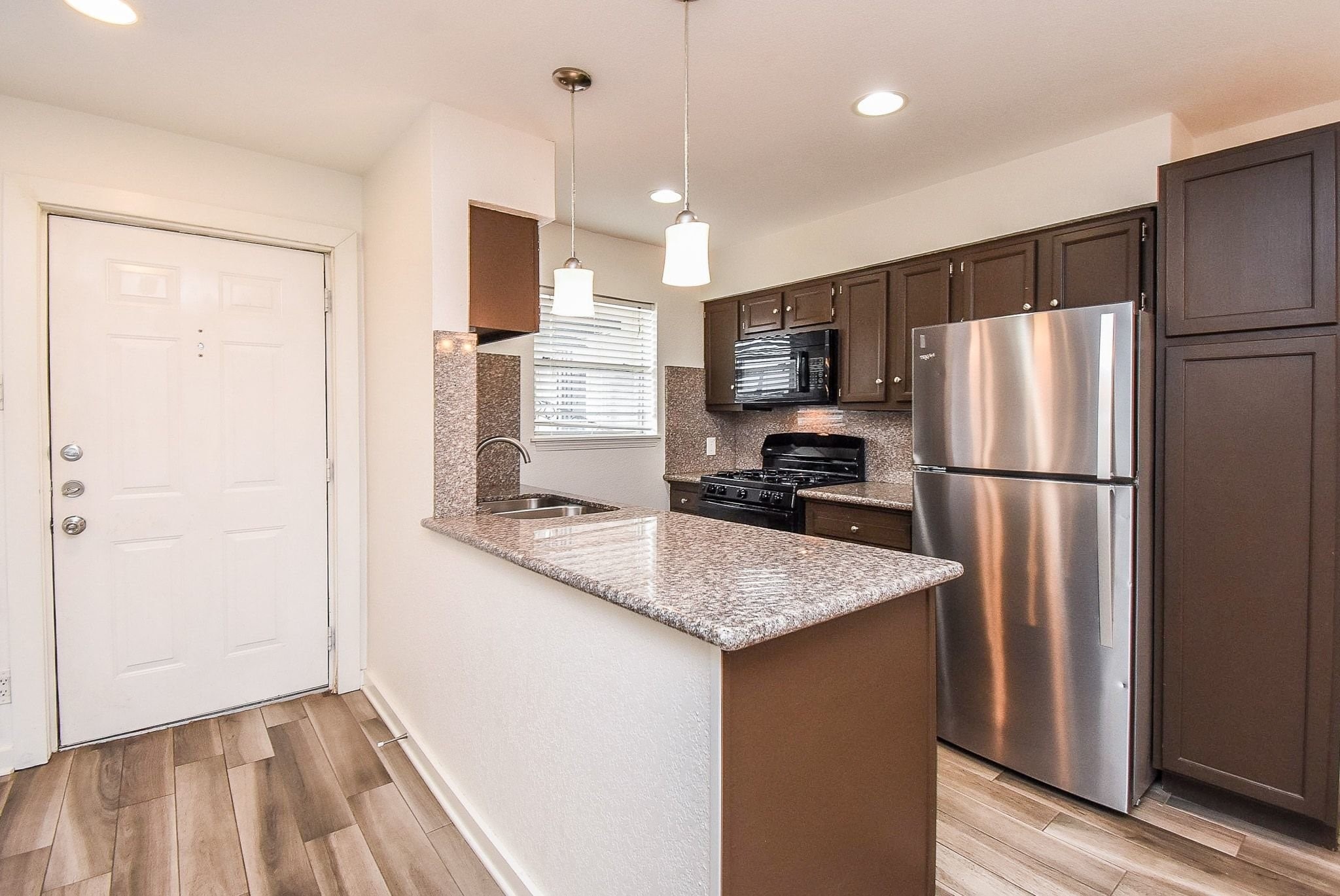 1404 Welch Street, Unit 2 Houston, TX 77006 - Photo 8 of 20 Bright and inviting kitchen with granite surfaces, modern finishes, recessed lighting, and convenient breakfast bar overlooking the main living space.
