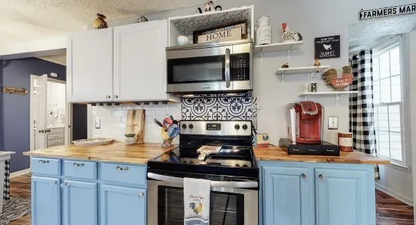 a kitchen with stainless steel appliances granite countertop a stove top oven a sink dishwasher and a microwave oven on the wooden floor