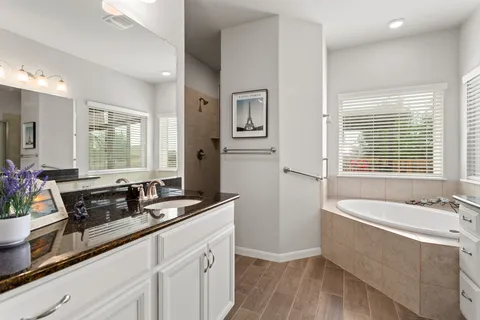 a bath room with a sink a mirror a window and a shower