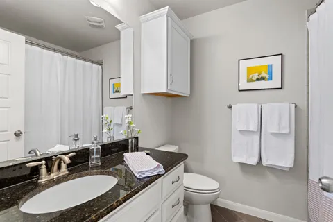 a bathroom with a granite countertop sink toilet and a mirror