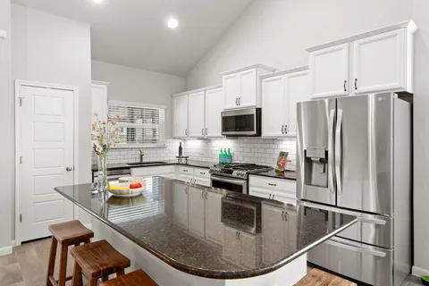 a kitchen with stainless steel appliances granite countertop a sink stove and refrigerator