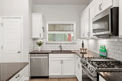 a kitchen with granite countertop a sink stove and cabinets