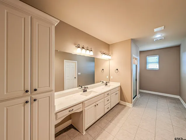 a spacious bathroom with a double vanity sink a mirror and a bathtub